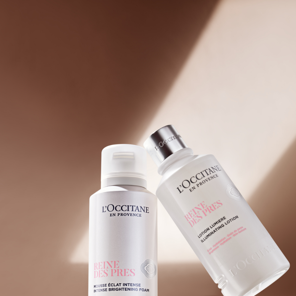 Productos L'Occitane en Provence de la línea Reine des Prés: espuma limpiadora Mousse Éclat Intense y loción iluminadora Lotion Lumière sobre un fondo minimalista con sombras de luz natural